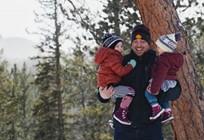 a dad holding his two children and walking in the snow